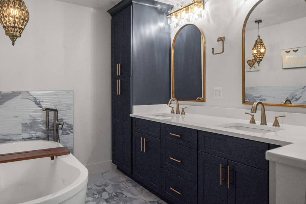 Luxurious modern bathroom with navy blue cabinetry, gold hardware, and marble accents, showcasing custom design and build services by Aurea Kitchens.