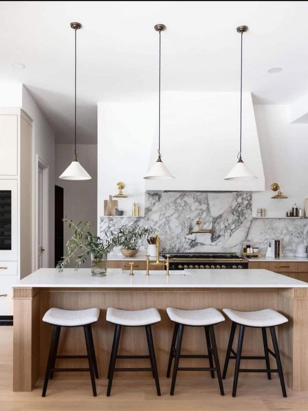 Sleek modern kitchen with marble backsplash, gold accents, and minimalist design in a luxury home. Features a large island with seating, pendant lighting, and custom cabinetry. Perfect for contemporary kitchen remodels.