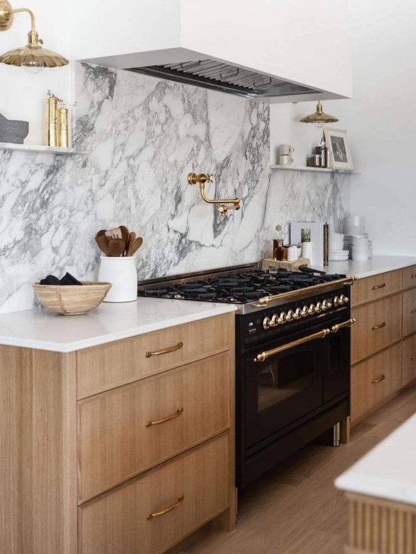 Aurea Kitchens modern kitchen with marble backsplash, natural wood cabinetry, and gold accents, showcasing custom design and build services for elegant, functional kitchen spaces.