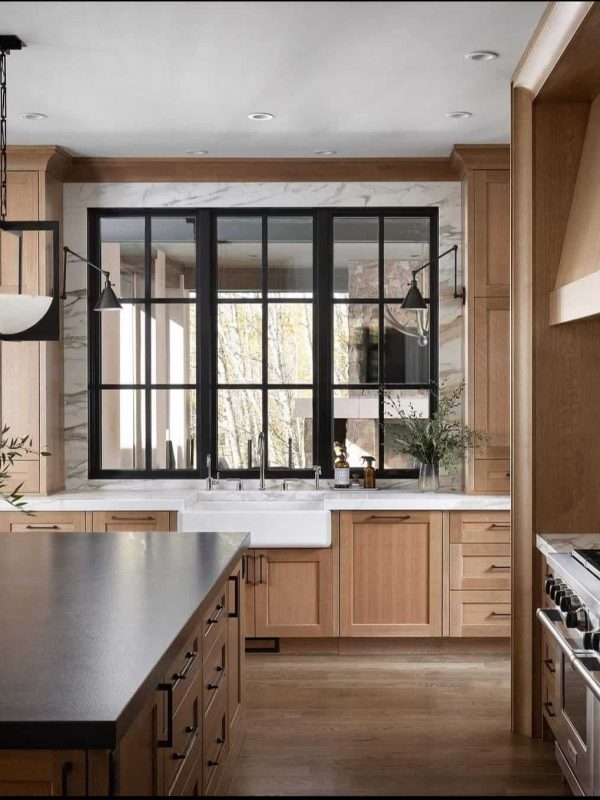 Modern farmhouse kitchen with black-framed windows, natural wood cabinetry, and a sleek marble backsplash, designed by Aurea Kitchens for stylish cooking and entertaining.