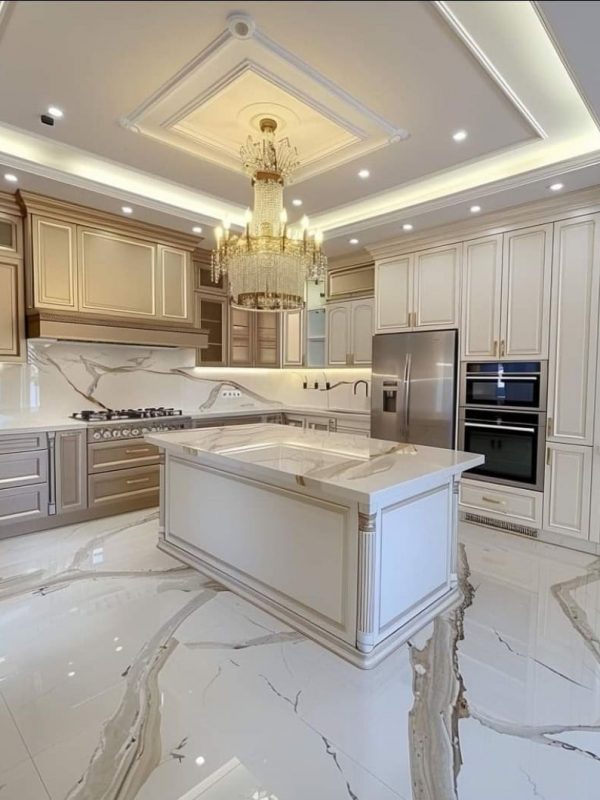 Luxurious modern kitchen with elegant cabinetry, marble countertops, and a grand chandelier, showcasing custom kitchen design and high-end kitchen renovation by Aurea Kitchens.
