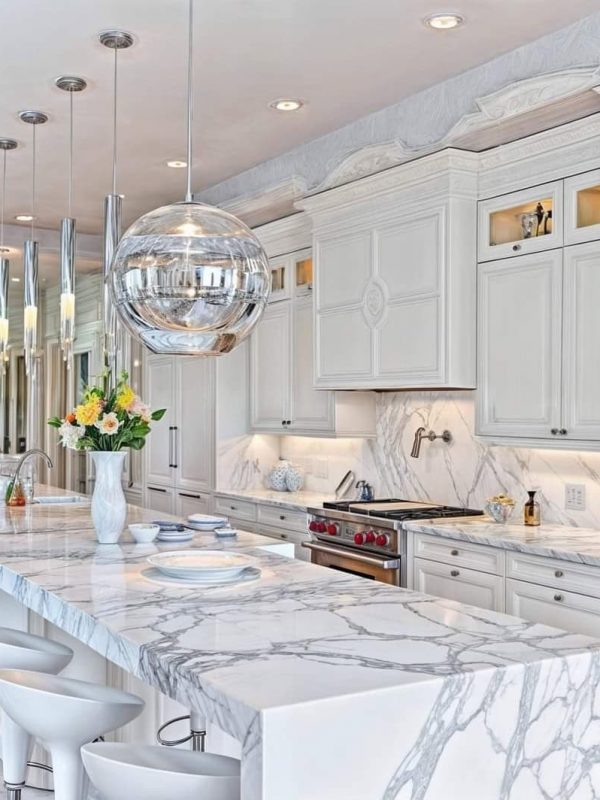Luxurious white marble kitchen with custom cabinetry and modern pendant lighting, showcasing high-end kitchen design and build services by Aurea Kitchens.