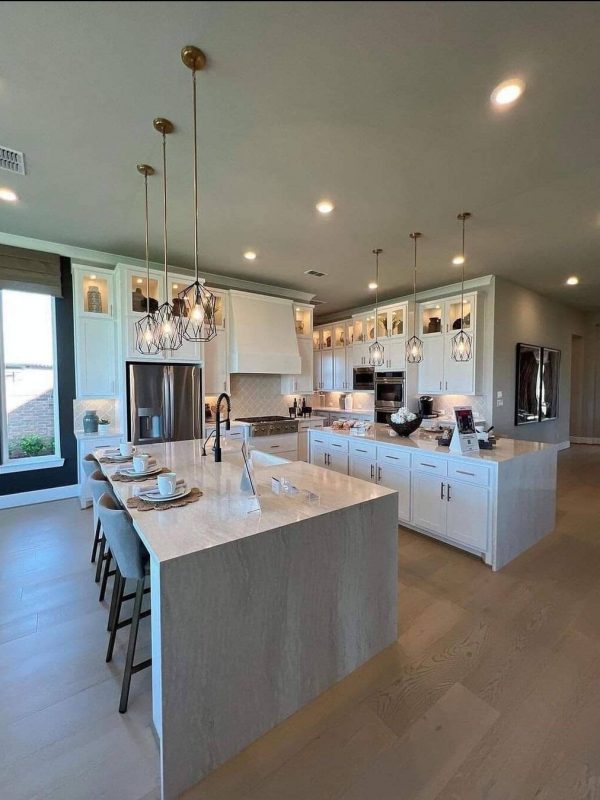 Bright white modern kitchen with oversized island, pendant lighting, and custom cabinetry, designed for functionality and style, perfect for entertaining and family gatherings.