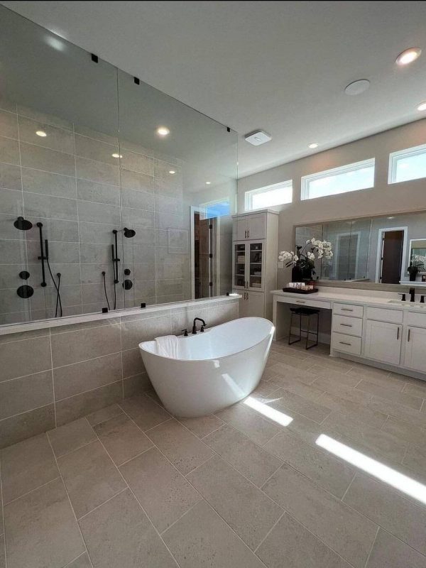Elegant bathroom with a modern freestanding bathtub, spacious glass-enclosed shower, and contemporary vanities, showcasing luxurious design and premium materials from Aurea Kitchens.
