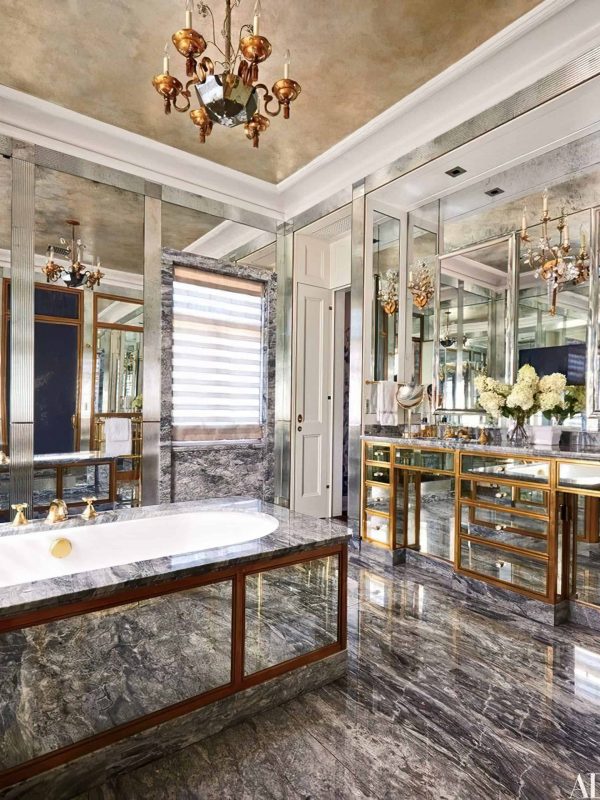 Luxurious marble bathroom with gold accents, mirrored cabinets, elegant chandelier, and a freestanding tub, showcasing premium design and build quality by Aurea Kitchens.