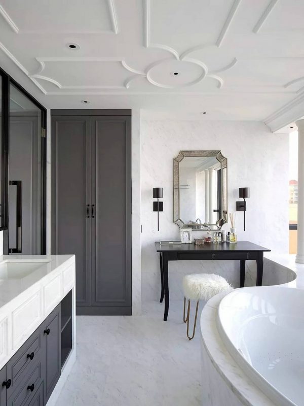 Luxurious modern bathroom with elegant black and white cabinetry, freestanding bathtub, stylish mirror, and large windows offering natural light, showcasing bespoke design and high-end finishes.